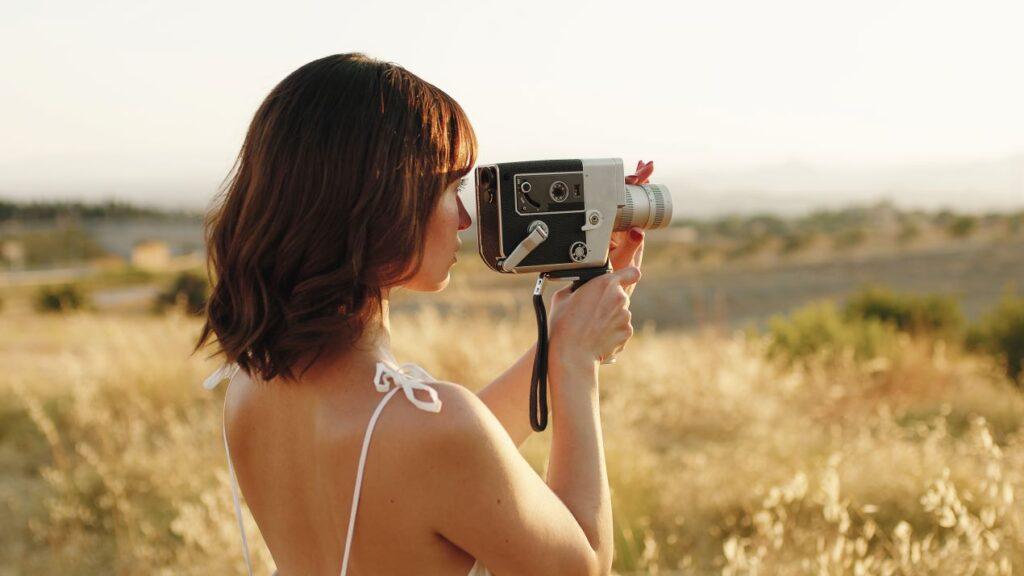 Frau mit einer klassischen Super8-Kamera in der Natur, ideal für Beiträge über Super8 digitalisieren und Erinnerungen.