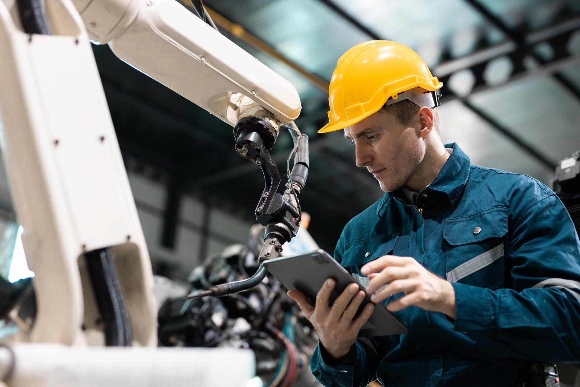 Mann mit Schutzhelm bedient Roboterarm mit Tablet | 2 Ohr Schlauchklemme